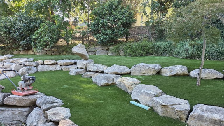 Boulder placement with plate compactor during landscape construction - Pro Step Landscaping Sydney