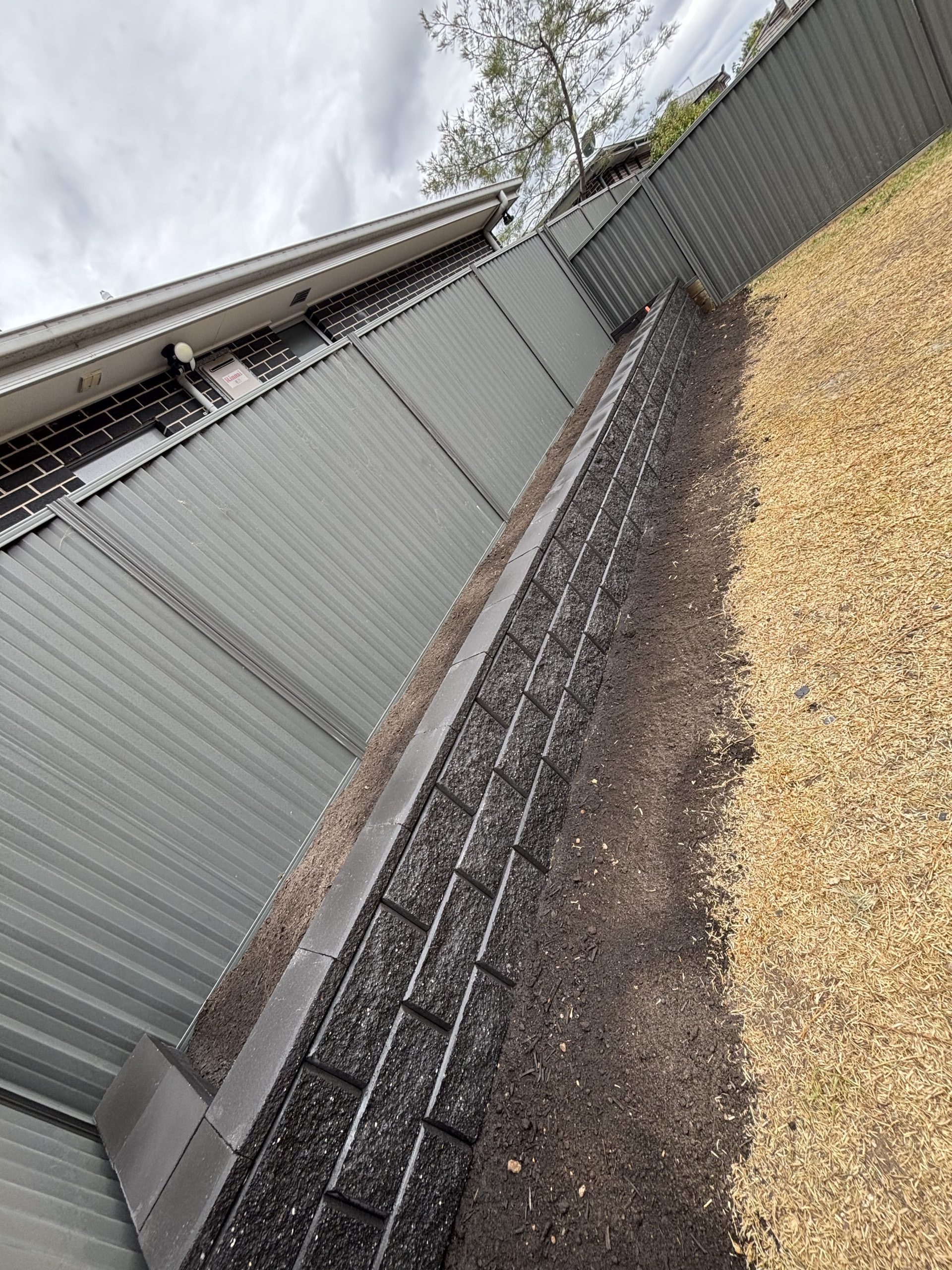 Retaining wall with garden bed edge along property perimeter in Sydney by Pro Step Landscaping