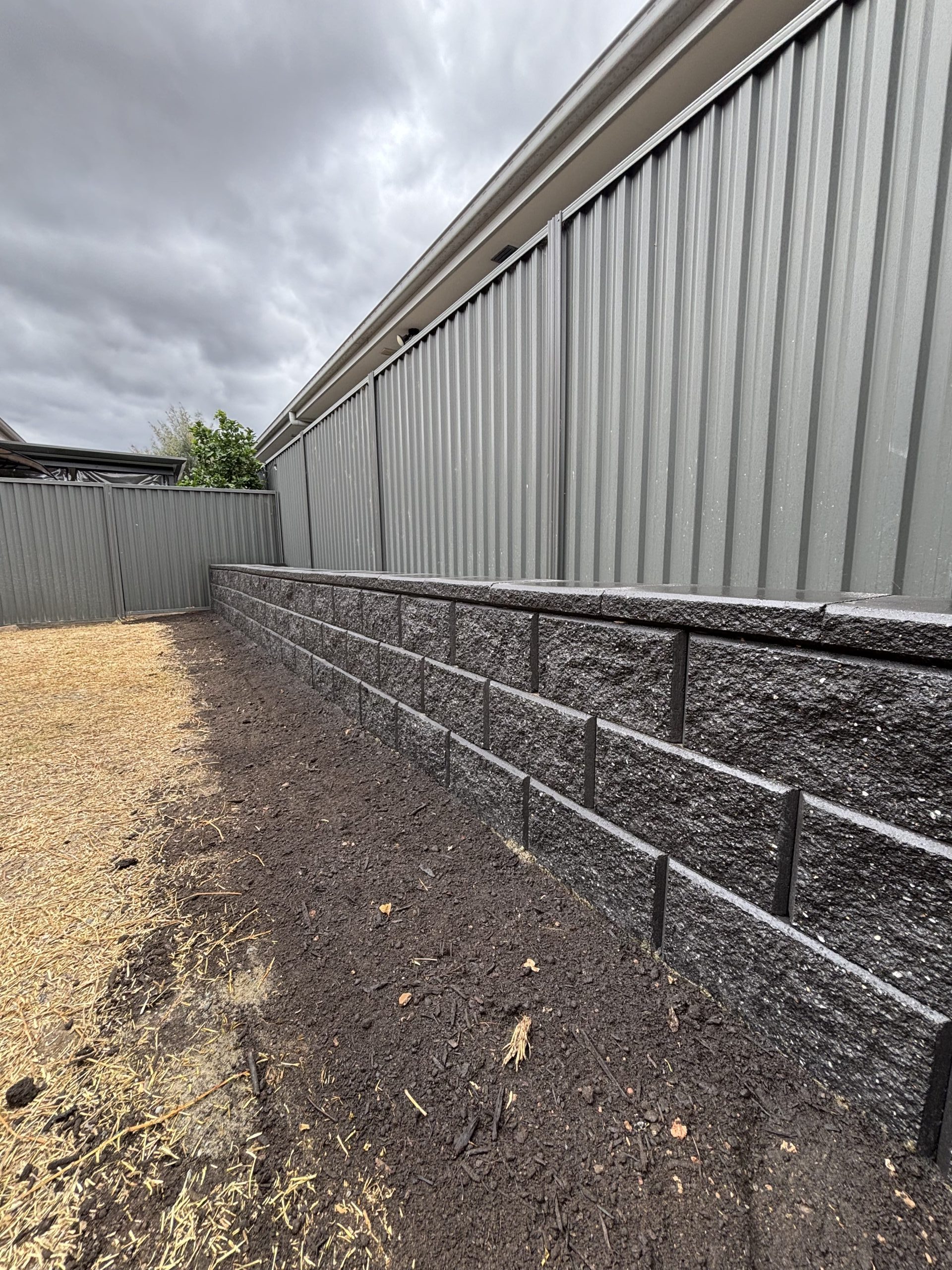 Close-up of retaining wall installation with metal fence in Sydney by Pro Step Landscaping