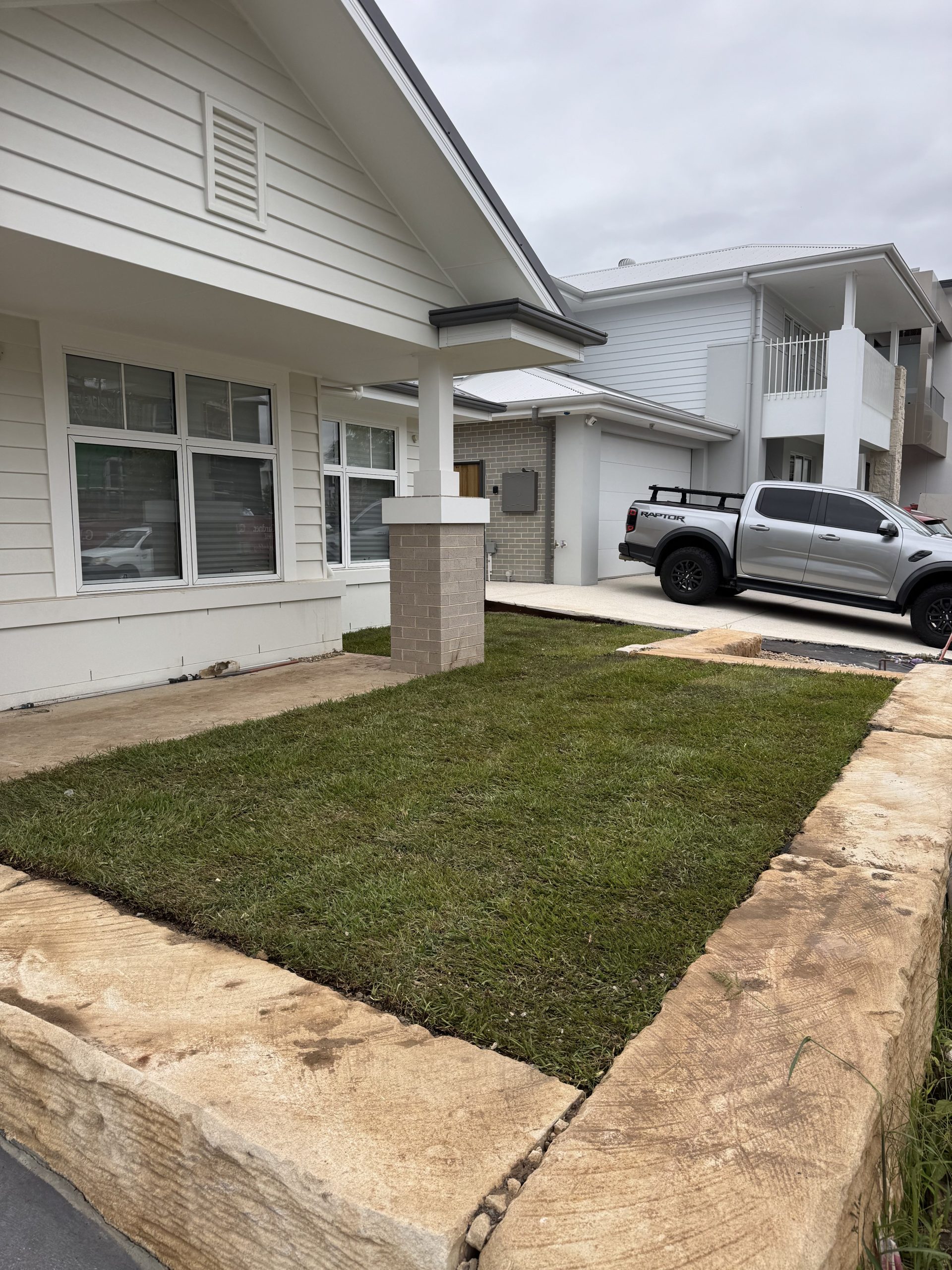 Freshly installed natural lawn with sandstone retaining wall border - Pro Step Landscaping Sydney