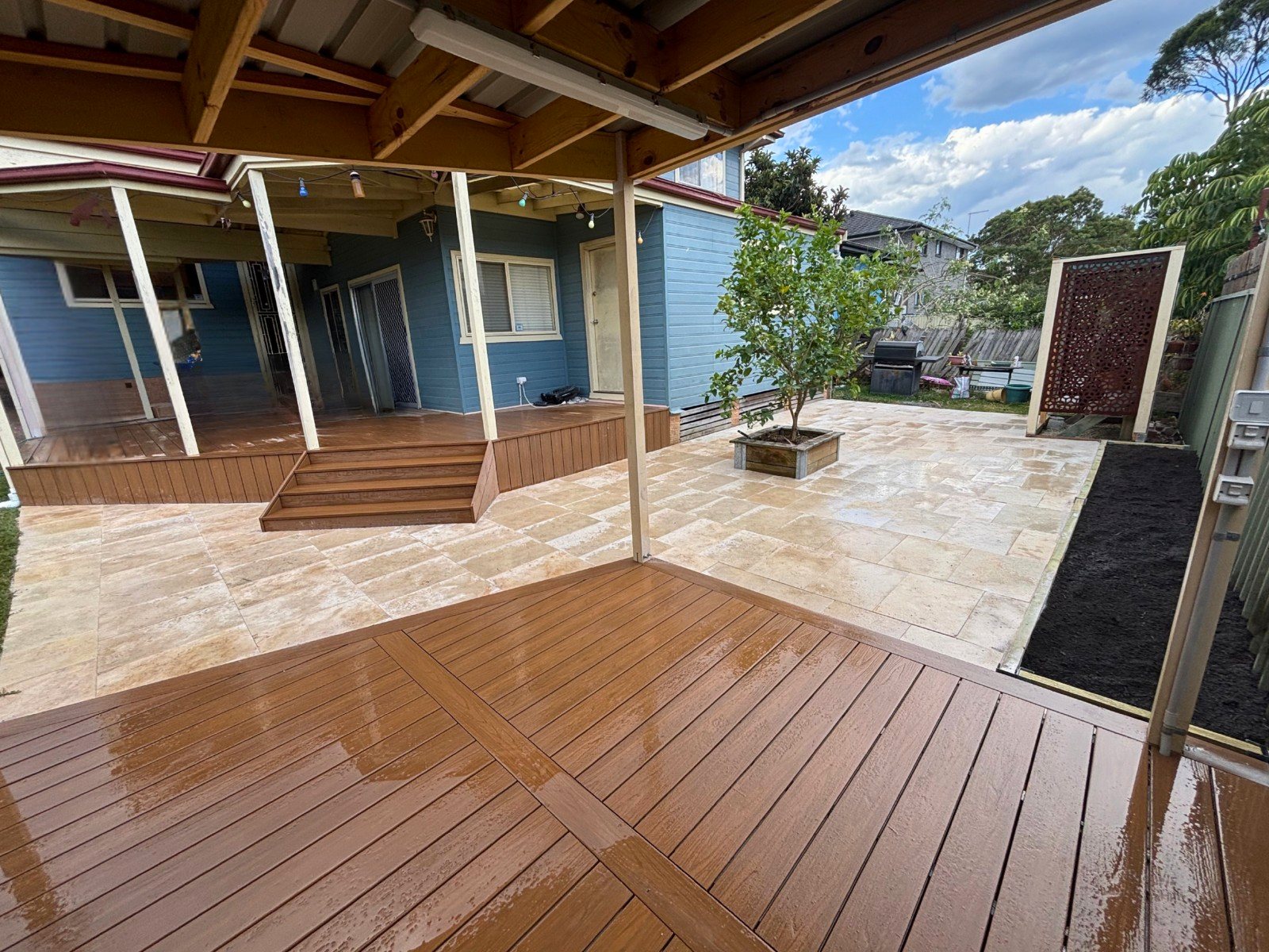 Travertine paving with garden bed and timber deck - backyard transformation by Pro Step Landscaping Sydney